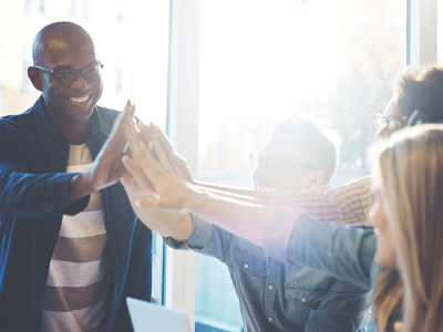Workers High Fiving With Sun Glare Behind Them