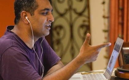 Man With Earbuds in Ears Pointing at Computer Screen